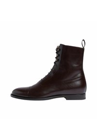 Stivaletto in pelle marrone con punta arrotondata, chiusura con lacci e occhielli metallici decorativi. Presenta una texture liscia e un tacco corto.