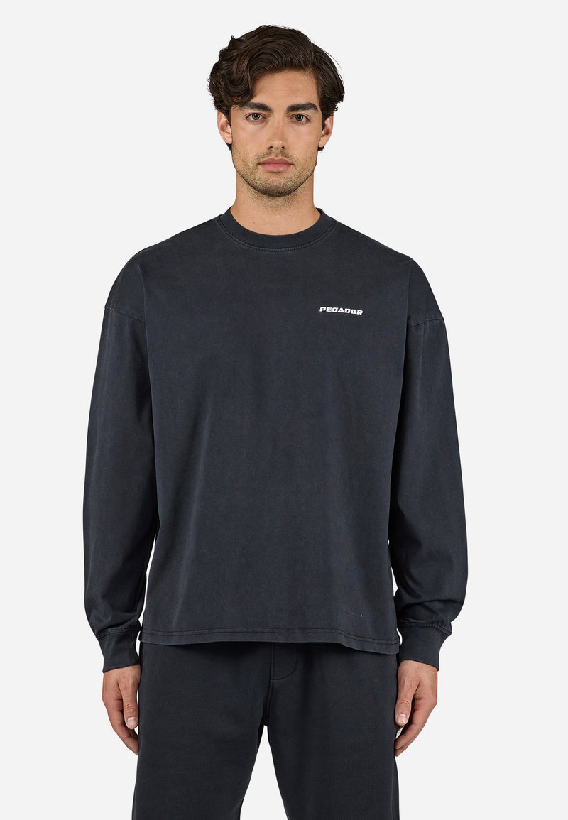 Dark gray long-sleeve sweatshirt made of cotton with a crew neck, featuring a small white "PEGADOR" logo on the chest. Simple design.
