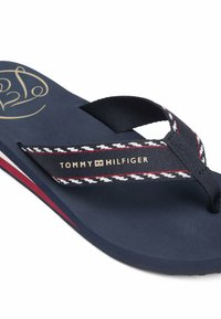 Infradito blu navy con una fascia intrecciata con accenti rossi e bianchi, una soletta testurizzata e dettagli del logo sulla fascia.