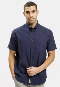 Koszula z krótki rękawem, zapinana na guziki, w ciemnym granatowym kolorze, z kieszonką na piersi, kołnierzykiem i fakturowanym materiałem.