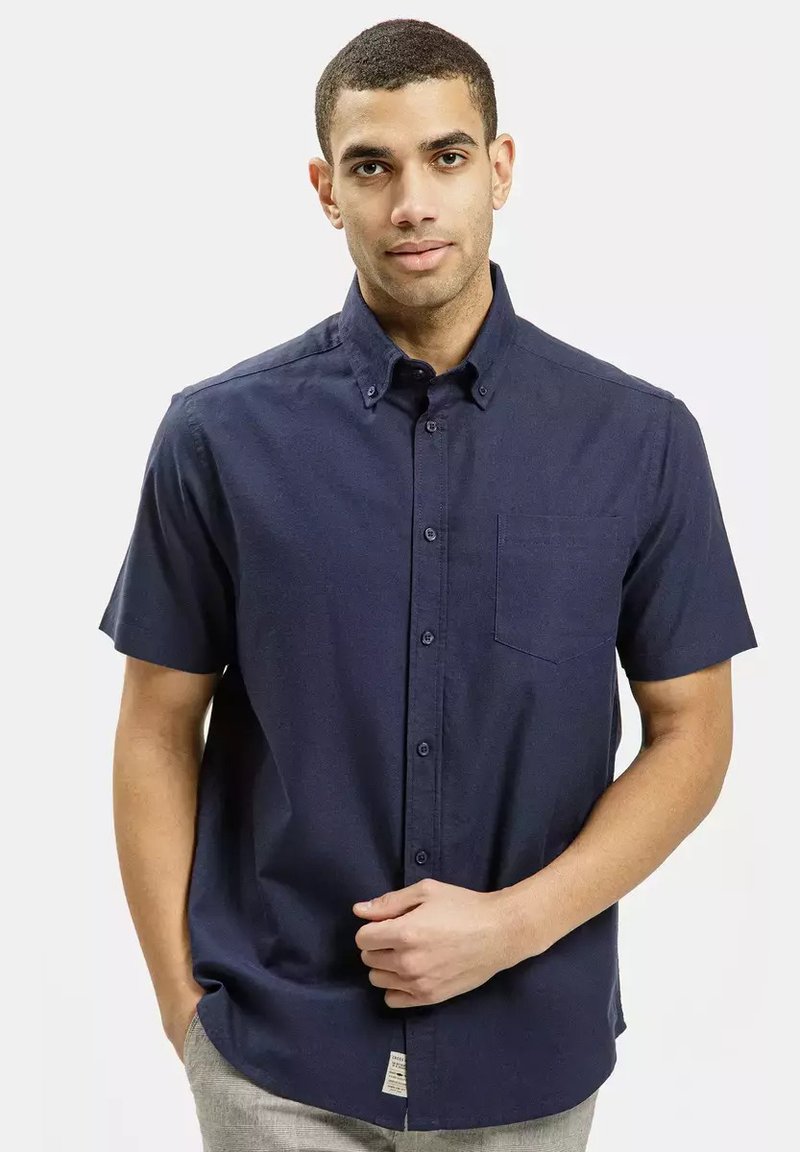Koszula z krótki rękawem, zapinana na guziki, w ciemnym granatowym kolorze, z kieszonką na piersi, kołnierzykiem i fakturowanym materiałem.