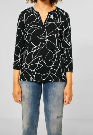 Zwarte top met witte abstracte lijnpatronen, driekwartmouwen en een notch-kraag. Draag het met versleten blauwe jeans.