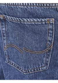 Jeans de denim azul con un bolsillo trasero que presenta costuras en color naranja y un patrón sutil en la tela. La vista en primer plano resalta las texturas y los detalles.