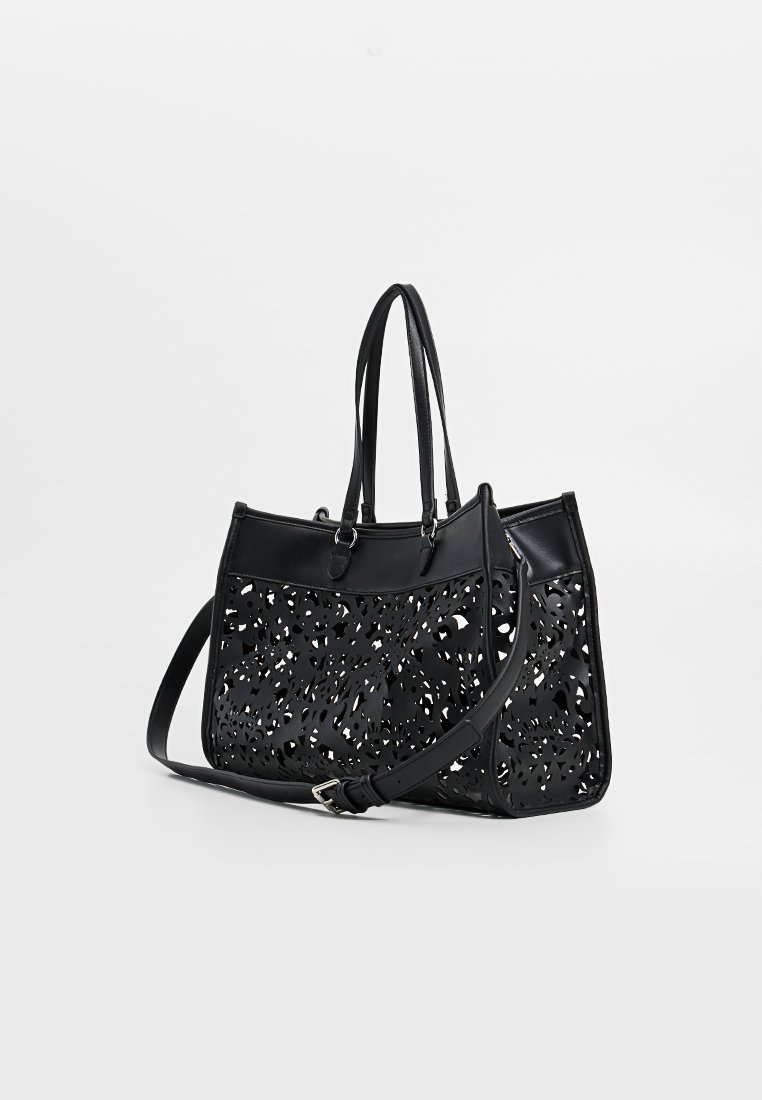Bolso tote negro con patrón floral recortado, doble asa y correa de hombro desmontable; hecho de material sintético con textura suave.
