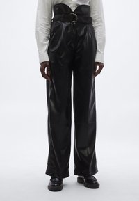 Svarta läderbyxor med hög midja och vida ben, utrustade med ett texturerat bälte och en glansig yta. Slät yta med minimala detaljer.