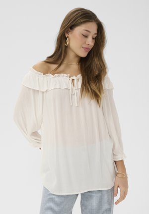 Biela blúzka s odhalenými ramenami, ozdobená volánmi, so šnúrkou na zaväzovanie a dlhými rukávmi; ľahká, prúdiaca látka s jemnou textúrou.