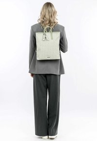 Sac à dos tissé de couleur vert clair, avec des poign�ées supérieures et des bretelles réglables, présentant une forme rectangulaire et un subtil détail de logo.