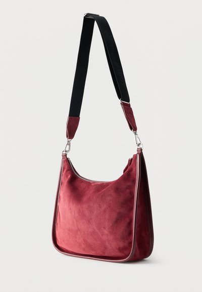 Κόκκινη τσάντα ώμου από σουέτ με μαύρο ρυθμιζόμενο ιμάντα και ασημένια κούμπωμα, με κλείσιμο με φερμουάρ στην πάνω άκρη.