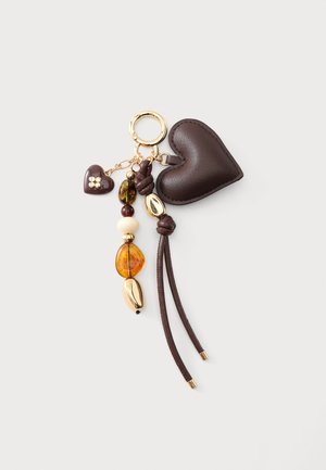 Porte-clés avec cœur en cuir marron foncé, petit charm cœur, perles d'ambre et d'or, et pampilles en cuir sur un anneau doré avec fermoir sur fond clair.