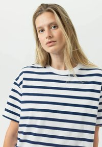 T-shirt en coton à rayures horizontales bleu marine et blanches, col rond et manches courtes. Texture douce et coupe décontractée.