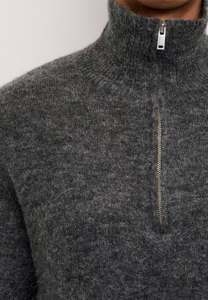 Maglione grigio lavorato a maglia con colletto alto e zip argentata a metà lunghezza. Tessuto strutturato e morbido con un aspetto lanuginoso.
