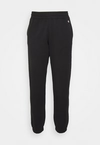 Pantalones de chándal negros con cintura y puños elásticos, fabricados en una tela suave, que presentan un pequeño logo en el lado izquierdo.