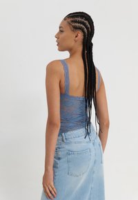 Blauwe kanten bodysuit met brede banden, voorzien van een doorzichtig ontwerp en bloemenpatroon, gecombineerd met een lichtgewassen denimrok.