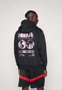 Black hoodie with a large pink NBA graphic on the back, featuring two globe designs and "Portal to the Dream" text. Cotton material.