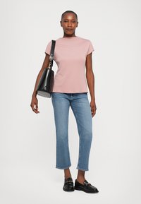 Light pink short-sleeve top, blue cropped jeans, and black loafers. Black handbag with strap. Smooth texture, fitted design, and casual look.