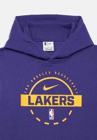 Violetinė ilgomis rankovėmis džemperis su kengūros kišene. Ant jo pažymėta "LOS ANGELES BASKETBALL" ir "LAKERS" geltonomis raidėmis. Įtraukta Nike logotipas ir NBA emblema.