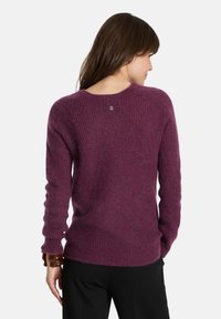 Lila gestrickter Pullover mit strukturiertem Finish und langen Ärmeln. Verfügt über einen runden Halsausschnitt und ein kleines Logo-Detail auf der Rückseite.