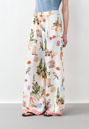 Wide white pants with colorful prints of cacti, birds, cocktails, playing cards, lipstick, cowboy boots, and red chili peppers.
