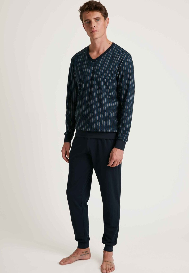 Navy Lounge-Set mit einem gemusterten langärmligen V-Ausschnitt-Oberteil und passenden tapered Hosen, aus weichem Stoff mit elastischen Bündchen.