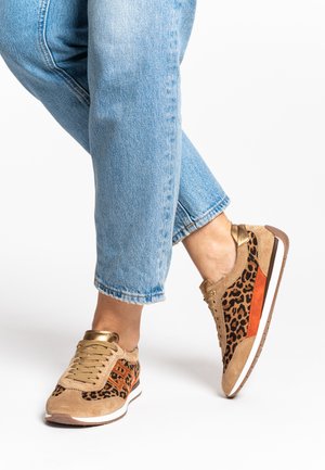 Tan suede sneaker with leopard print side panels, orange accents, and gold eyelets. Features a white sole and textured detailing.