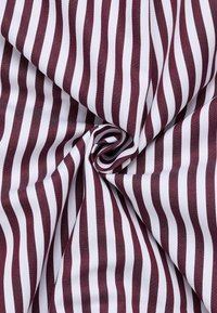 Tessuto rigato bordeaux e bianco con una texture liscia, che presenta linee parallele e uniformi in un motivo a spirale.
