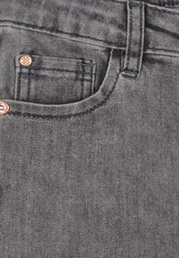 Ciemnoszare dżinsy o prostym kroju z przednią kieszenią, miedzianymi nitami i kontrastowymi przeszyciami. Materiał wydaje się miękki z delikatną teksturą.