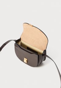 Borsa a tracolla in pelle marrone con una forma curva e un interno in suede. Chiusura in metallo dorato ben visibile e tracolla regolabile.