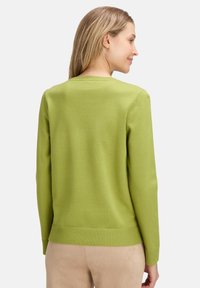 Zöld pulóver, puha anyagból, kerek nyakkivágással, bordás mandzsettával és aljjal. Simább textúra, látható minták nélkül.