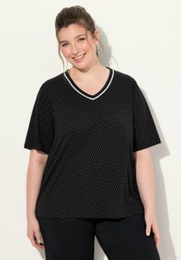 Zwart shirt met korte mouwen en witte stippen, V-hals met witte bies, gemaakt van zachte stof, met een losse pasvorm en zijzak.