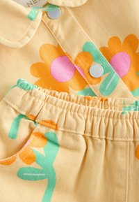 Material galben din catifea cu dungi, având modele mari de flori portocalii și roz cu accente verzi. Include un design cu guler și talie elastică.