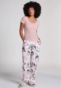 Rosa ribbad kortärmad topp med spetsdetaljer, parat med vita byxor med blommönster i gröna och rosa accenter, bärs med gråtofflor.