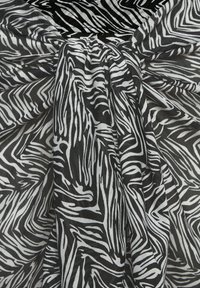 Schwarz-weißer, gestreifter Stoff mit einem zentralen Knoten, der Falten und dynamische kontrastierende Muster erzeugt.