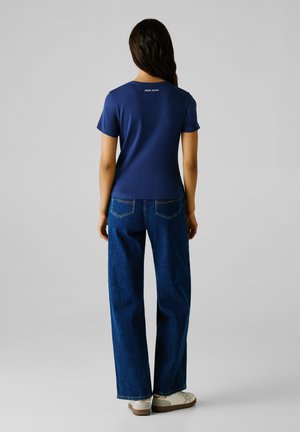 Marineblauw geribd t-shirt met korte mouwen en een ronde halslijn, met het "Pepe Jeans" logo op de achterkant, gecombineerd met hoge taille wijde jeans.