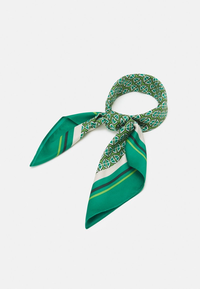 Foulard en soie vert avec des motifs géométriques et rayés, noué lâchement en boucle sur fond blanc.