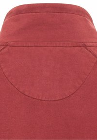 Tissu en coton rouge à texture lisse. Présente un col arrondi et des coutures contrastantes le long des coutures et des bords.