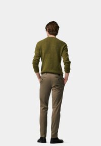 Olive green knit sweater with a rounded neckline, paired with beige slim-fit trousers and black shoes, viewed from the back.