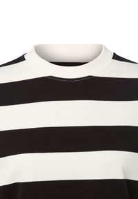 Koszulka z okrągłym dekoltem w szerokie poziome czarne i białe paski, z białym ściągaczem i widocznymi szwami przy dekolcie.