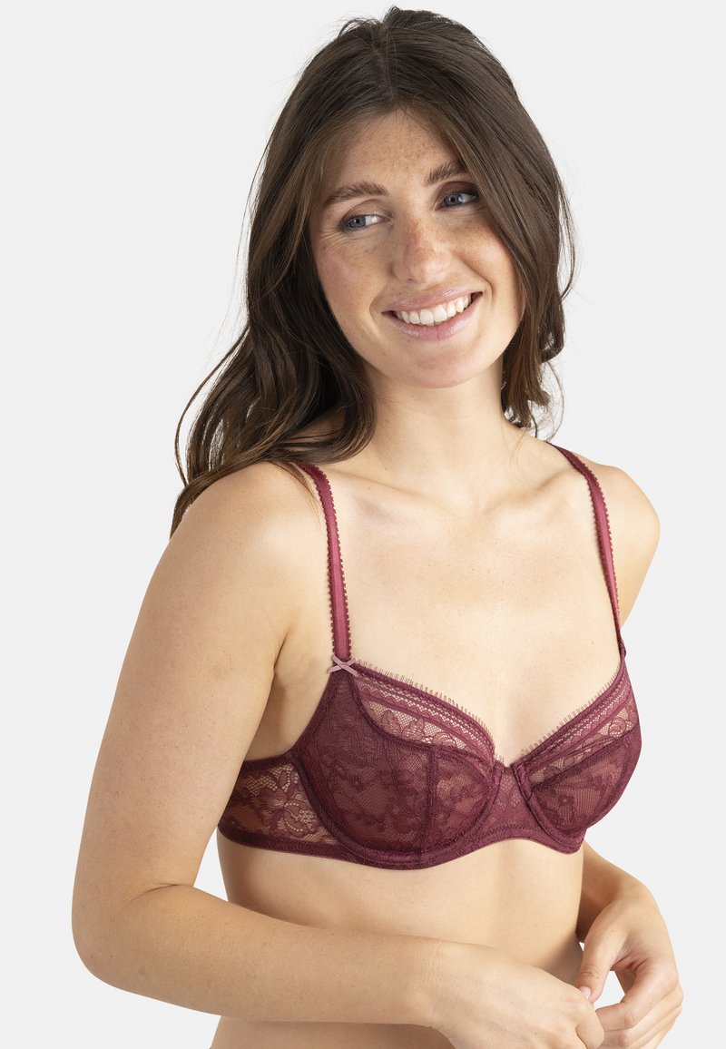 Soutien-gorge en dentelle bordeaux avec un motif floral transparent, support à armatures, bretelles réglables et bords festonnés. Texture douce avec un délicat nœud accent.