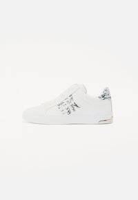 Sneaker bianca con tomaia liscia, logo in rilievo discreto, dettaglio del tallone con motivo e suola in gomma bianca. Caratterizzata da un design con lacci.