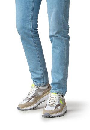 Baskets gris et blanches en daim et mesh, dotées d'une semelle épaisse et d'accents vert néon sur la marque et le talon.