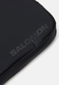 Salomon padded case in black, featuring a textured surface with a grid pattern, rounded corners, and embossed logo on the side.