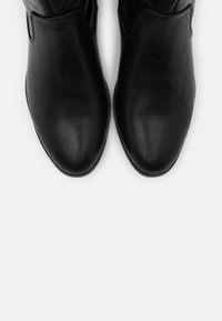 Black leather ankle boots with a smooth texture, rounded toe, and elastic side panels for easy wear. Flat rubber sole with minimal tread.