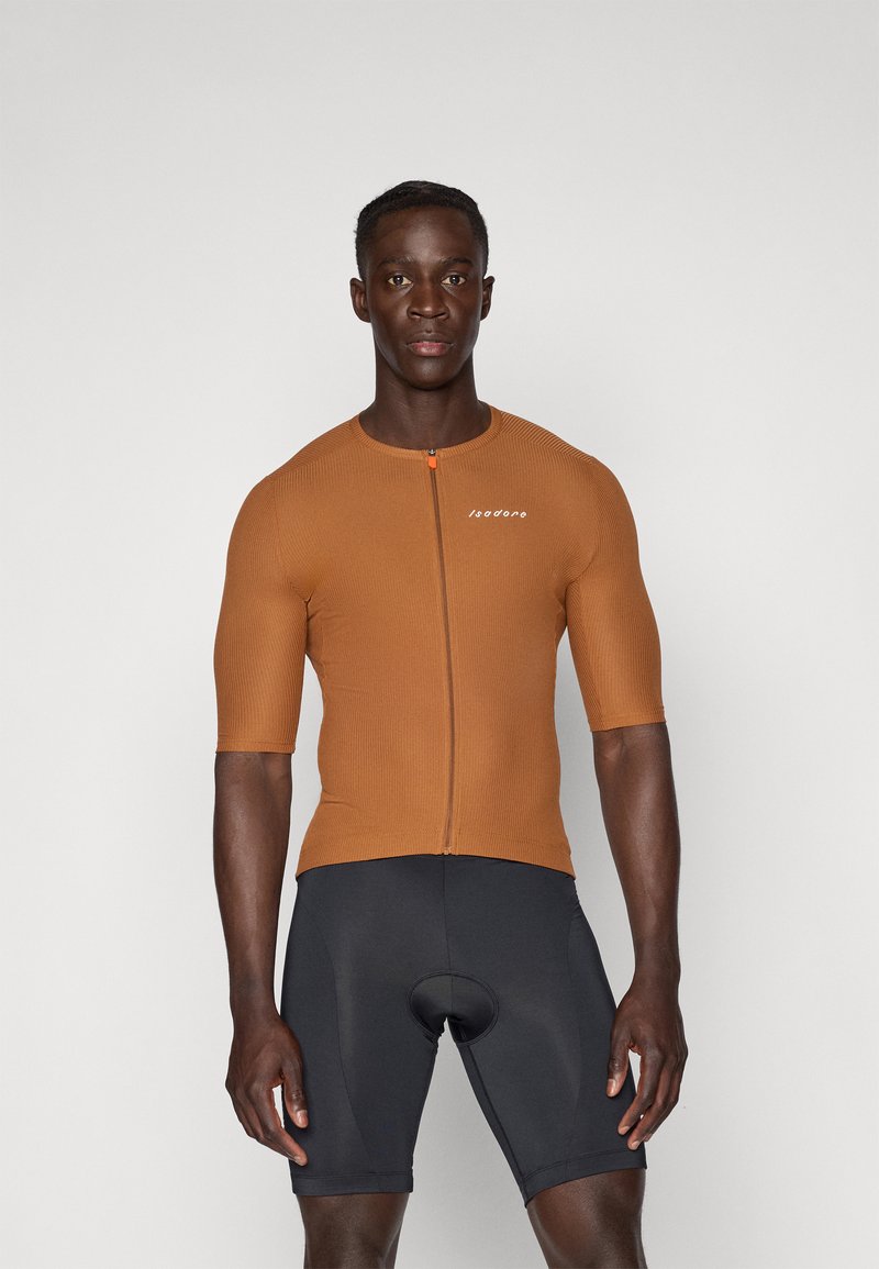 Brun, ribbet, kortermet sykkeltrøye med glidelås foran og logo. I kombinasjon med svarte sykkelshorts. Glatt tekstur, tettsittende design.