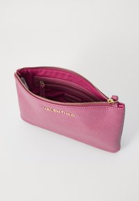 Rózsaszín bőr clutches táska texturált felülettel, arany cipzáras záródással és belső zsebekkel. Az elülső oldalon arany "VALENTINO" logóval.