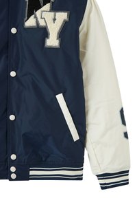Granatowa i kremowa kurtka varsity z białymi guzikami, boczną kieszenią, prążkowanym ściągaczem oraz puszystym napisem "NY" na klatce piersiowej.