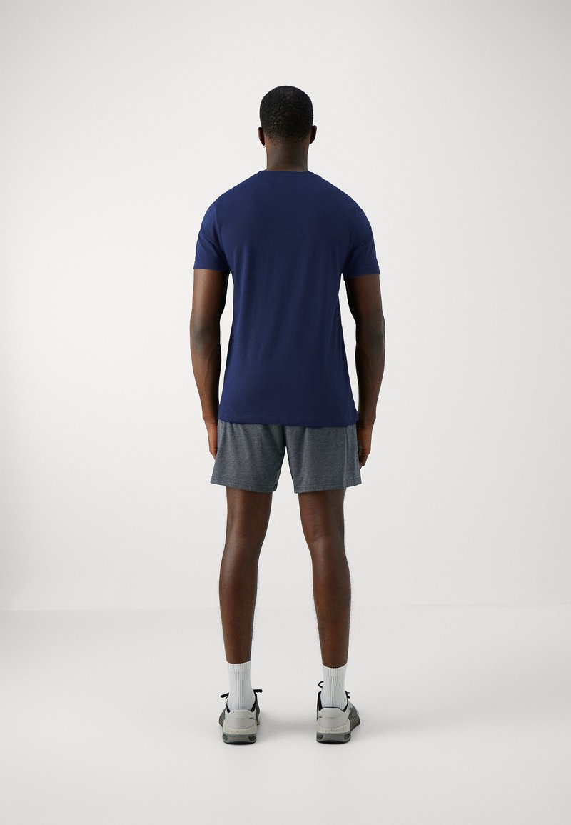 T-shirt bleu marine à manches courtes, col rond, porté avec un short de sport gris, vu de dos. Design simple, coupe décontractée.