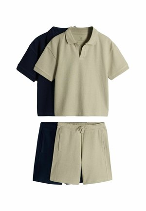 Twee geribbelde poloshirts en bijpassende short met trekkoord in beige en zwart, gestapeld met de beige set bovenop tegen een witte achtergrond.