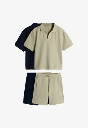 Twee geribbelde poloshirts en bijpassende short met trekkoord in beige en zwart, gestapeld met de beige set bovenop tegen een witte achtergrond.