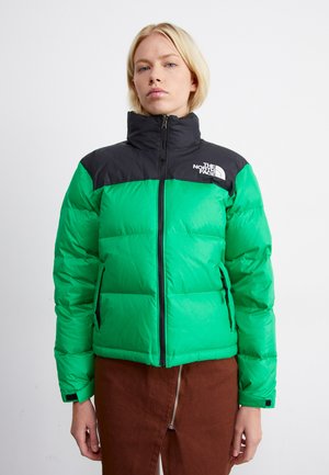 Groene pufferjas met zwart bovenstuk, hoge kraag en ritssluiting. Voorzien van een logo op de linkerborst en contrasterende materiaalkleur.