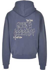 Kapucňová mikina v tlmenej modrej farbe, s bielym textom v graffiti štýle na zadnej strane, vyrobená z mäkkého materiálu, s rebrovanými manžetami a lemom pre tesný strih.